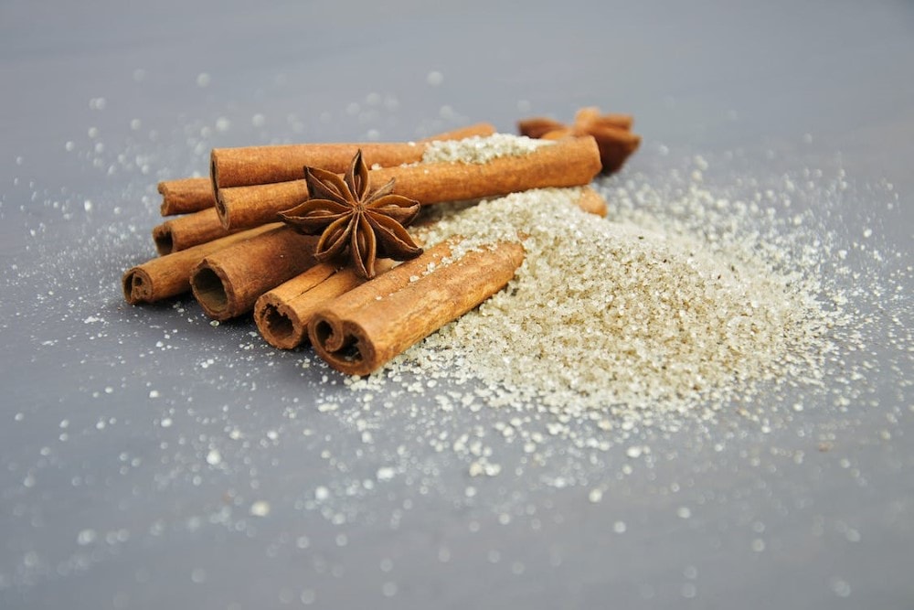 cinnamon sticks with star anise in small pile of raw sugar
