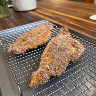 fried catfish cooling on a wire rack over cookie sheet on wooden kitchen counter