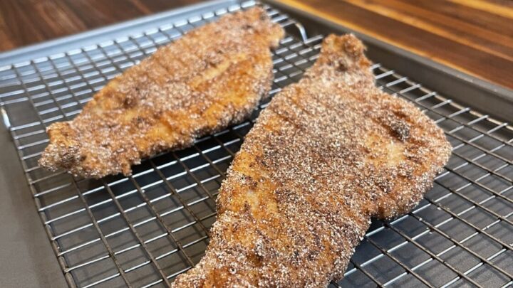 fried catfish cooling on a wire rack over cookie sheet on wooden kitchen counter