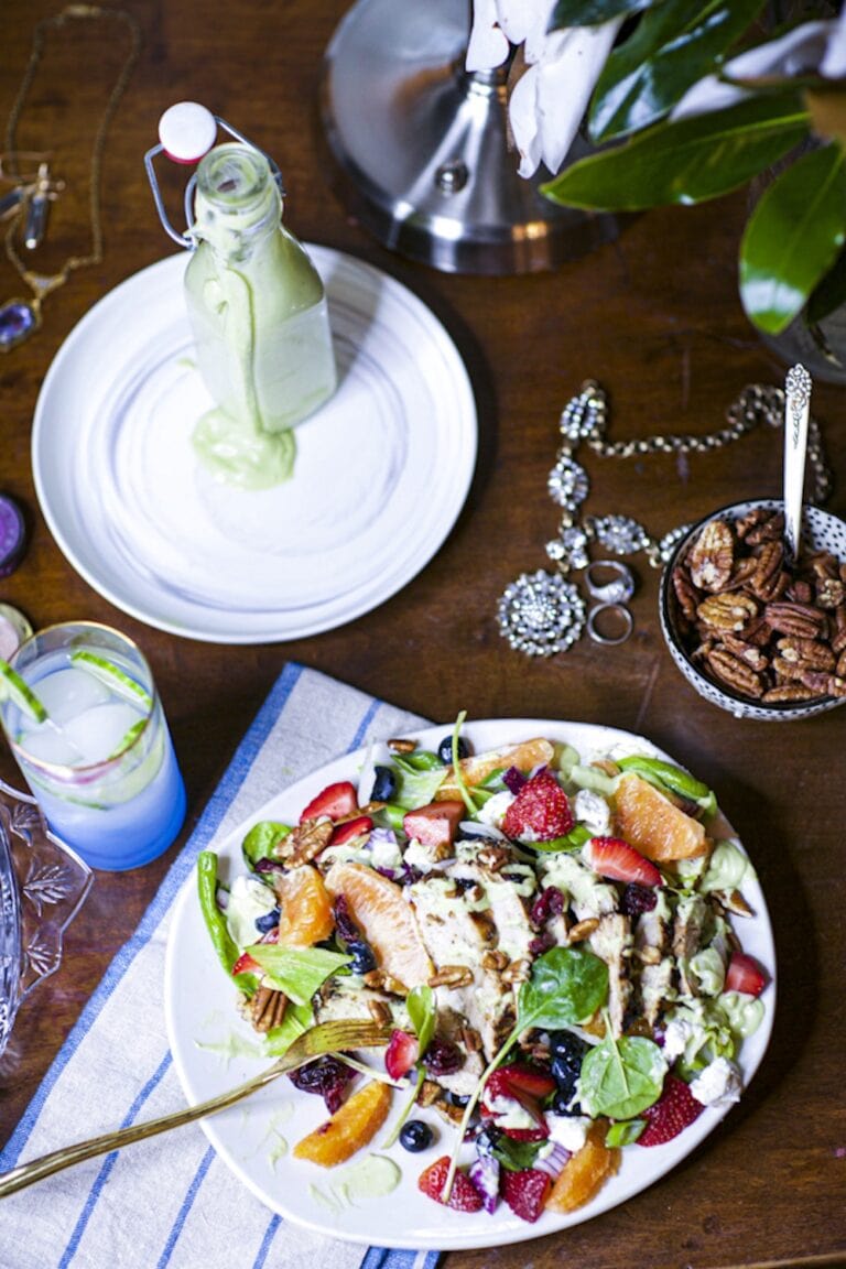 healthy salad with chicken in white bowl, drizzled with homemade avocado green goddess dressing
