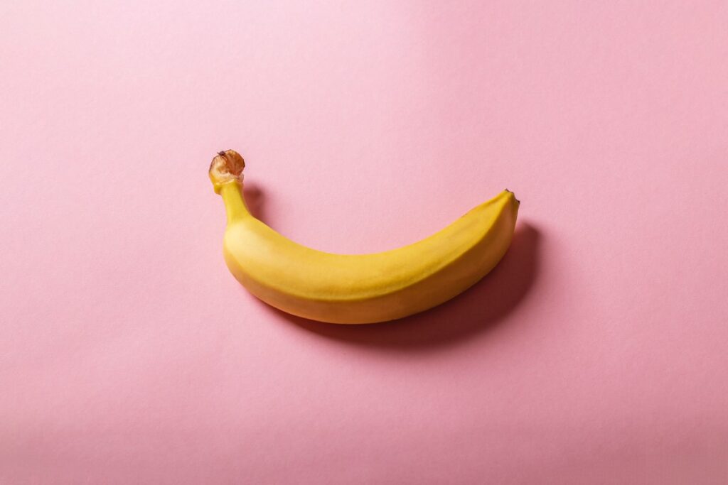 almost ripe banana on a pink background