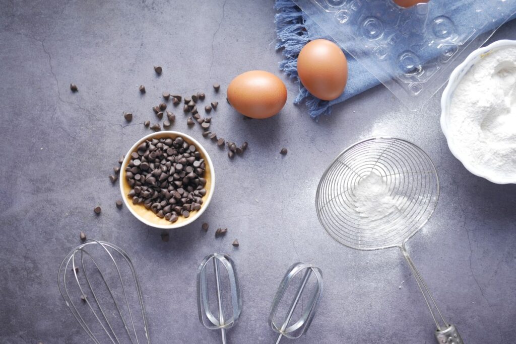 cooking ingredients: chocolate chips, two eggs, flour on table with blue napkin