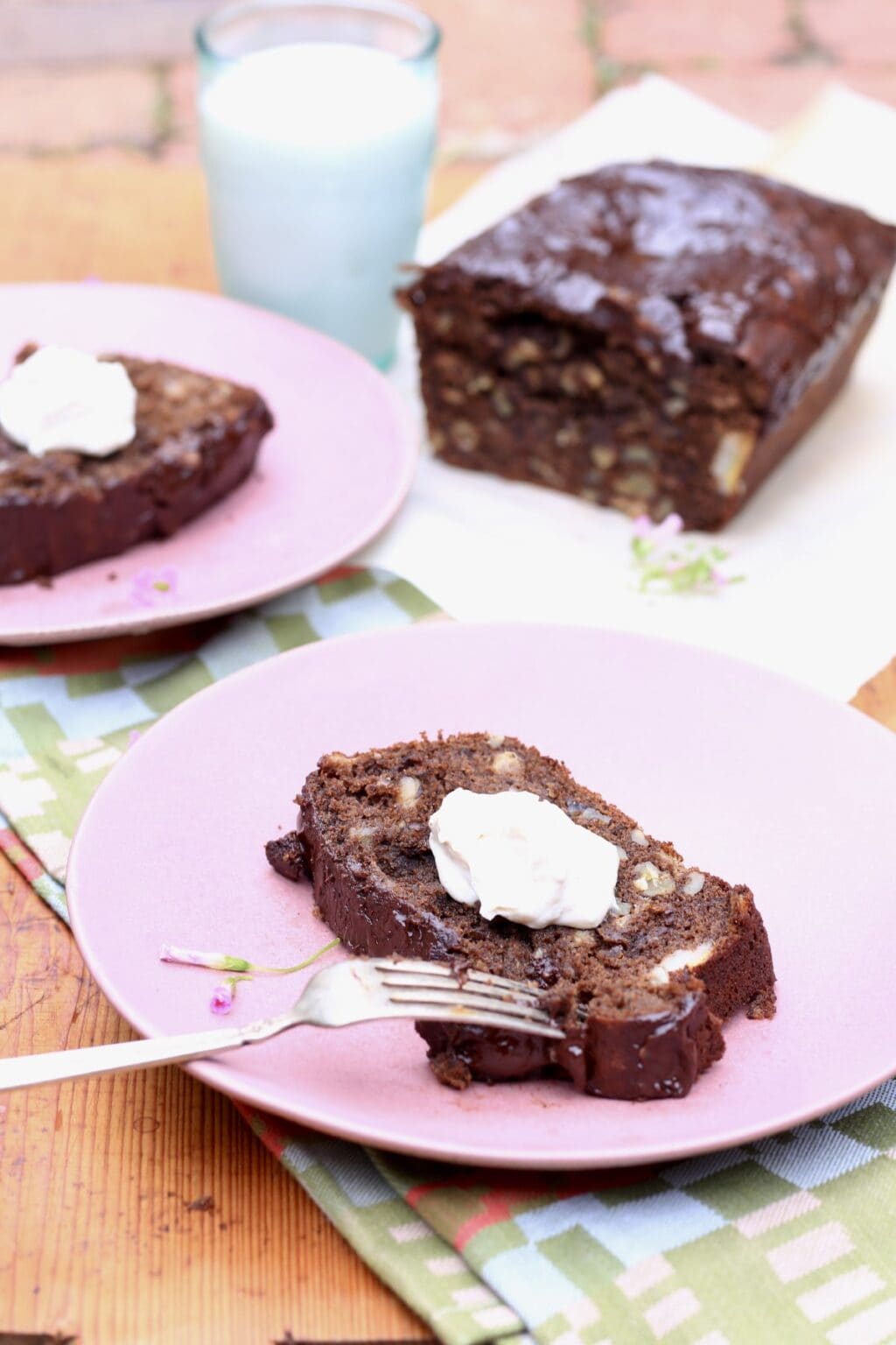 slices of healthy chocolate banana bread with butter on pink plates, banana quickbread loaf in background