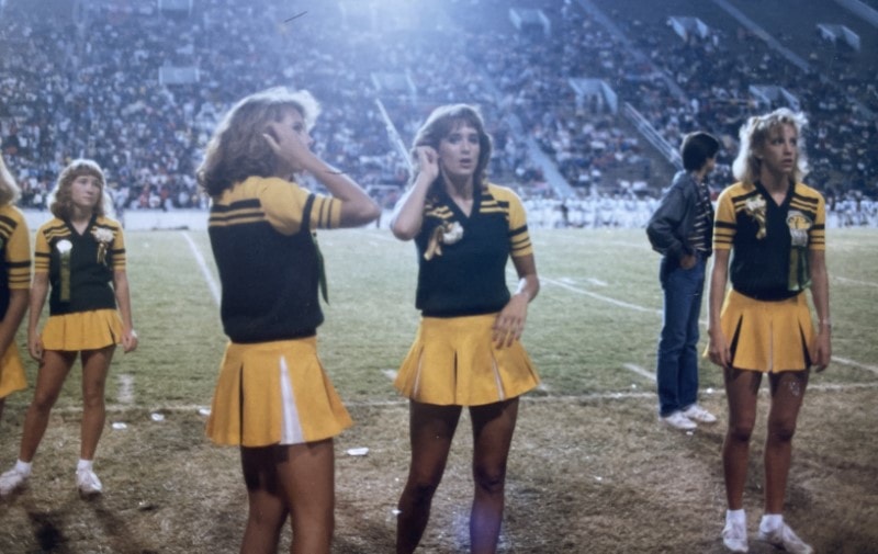 Stacy Lyn in group of high-school cheerleaders in black and gold outfits
