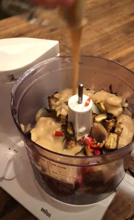 Adding ingredients of baba ganoush to food processor for blending