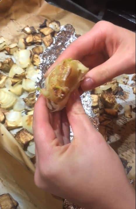 Stacy Lyn removing roasted garlic from baking sheet and squeezing it to extract the cloves