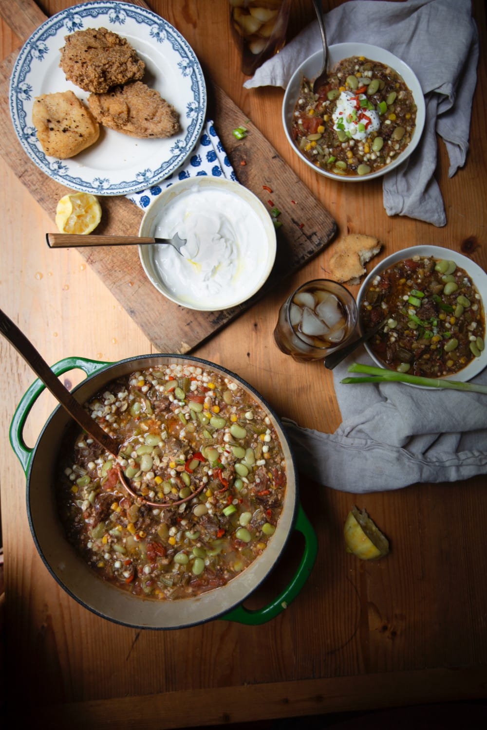 Stacy Lyn's vegetable beef soup in Dutch oven with ladle alongside bowls of soup on wooden table