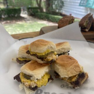 stack of venison copycat krystal burgers on white paper on plate in Stacy Lyn's backyard