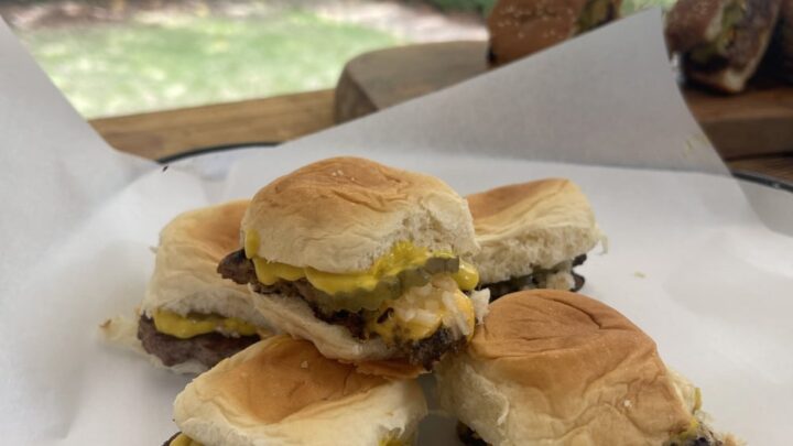 stack of venison copycat krystal burgers on white paper on plate in Stacy Lyn's backyard