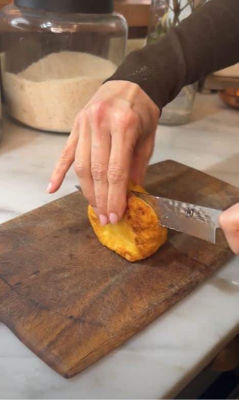 Stacy Lyn slicing arepas cornmeal cake in half on cutting board.