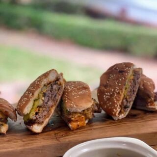 sriracha sauce on smashburgers cut in half with pickles
