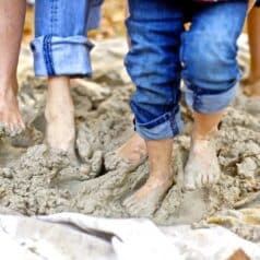 kids with rolled-up jeans mixing the sand and clay with bare feet