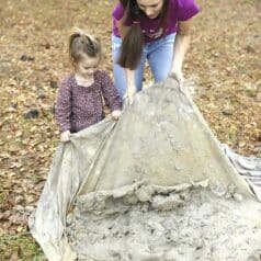 Stacy Lyn and small daughter lifting edge of tarp to start mixing the sand and clay with water