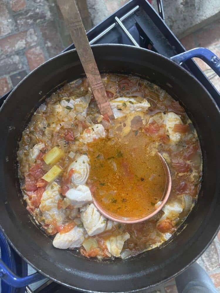 fisherman's stew cooking outdoors in large cast-iron pot