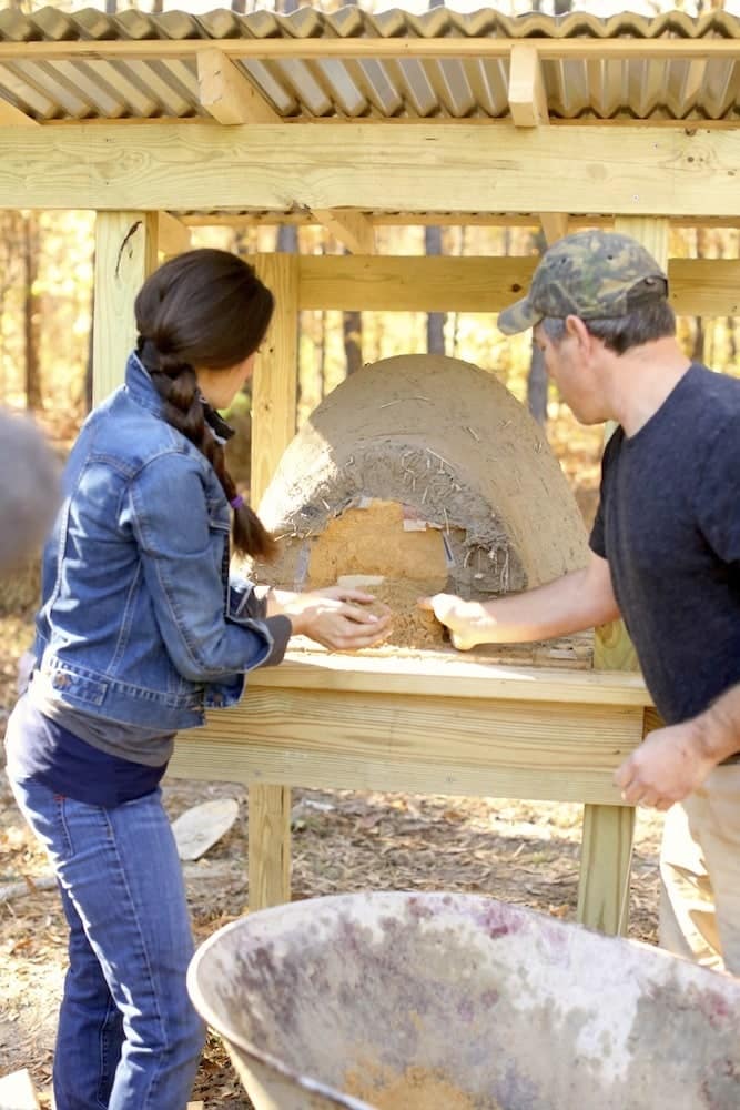 Stacy Lyn and Scott building an earthen oven - scooping out the sand form from inside the hardened mud dome