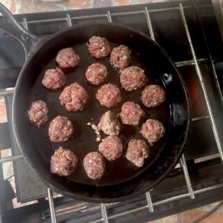 turkey sausage balls cooking in cast iron pan