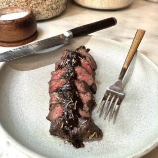 venison medallions with cabernet mushroom sauce on white plate with fork and knife