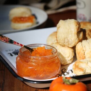persimmon jam in jar with knife on counter