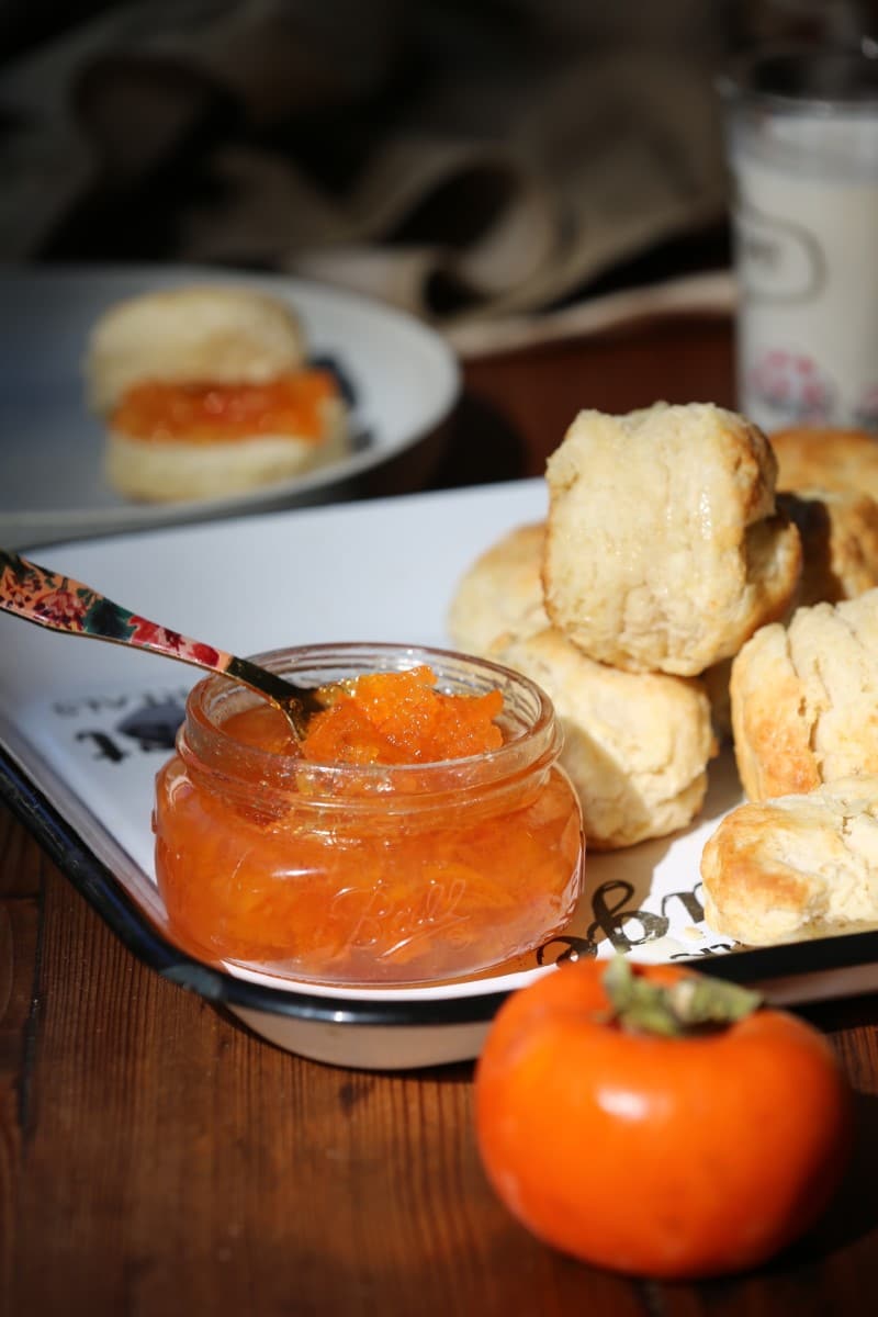 persimmon jam in jar with knife on counter