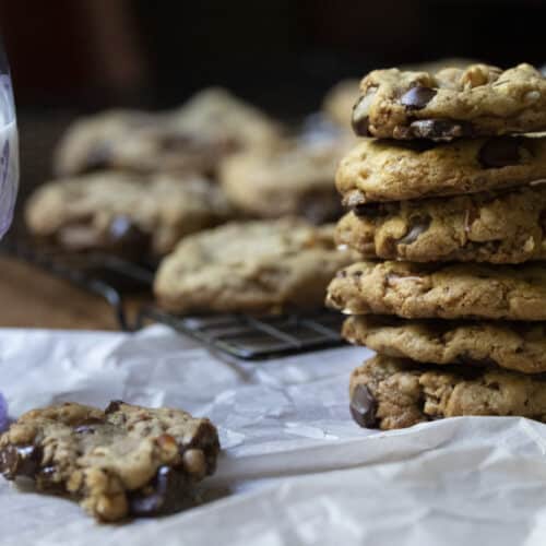 A stack of freshly baked kitchen sink cookies next to a cookie with a bite out of it