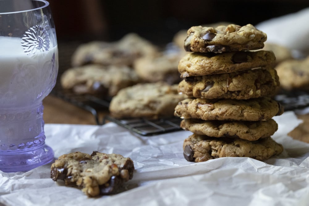 A stack of freshly baked kitchen sink cookies next to a cookie with a bite out of it