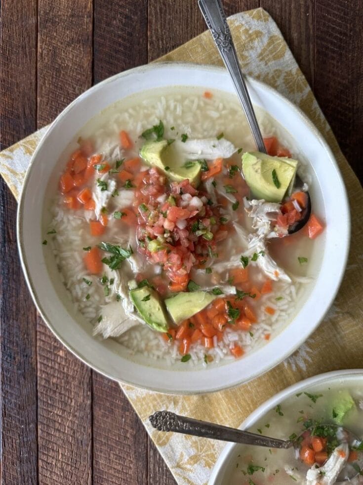 Bowl of Mexican chicken soup - callo de pollo - with chicken, rice, pico de gallo, and avocado