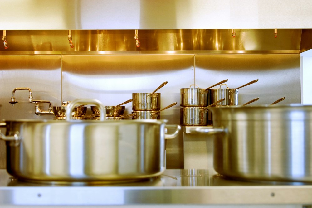 stainless steel pots and pains lined up and stacked in commercial kitchen