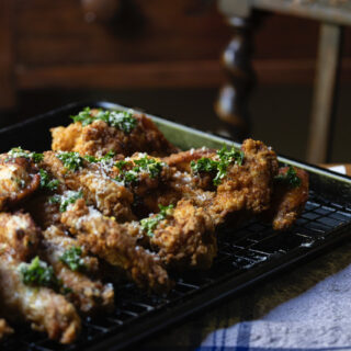 fried chicken wings with honey garlic sauce cooling on wire rack on kitchen table with striped blue cloth