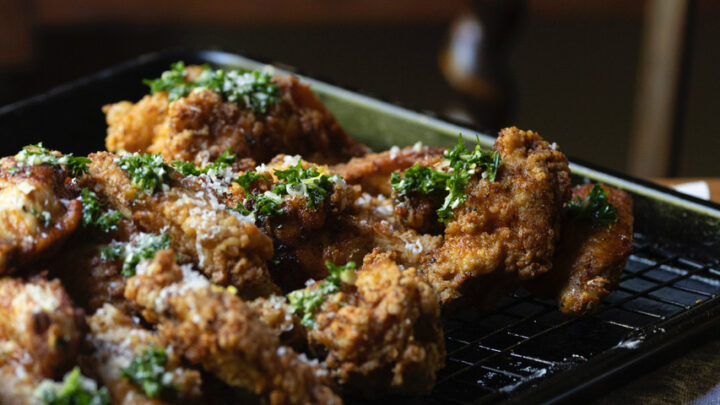 fried chicken wings with honey garlic sauce cooling on wire rack on kitchen table with striped blue cloth