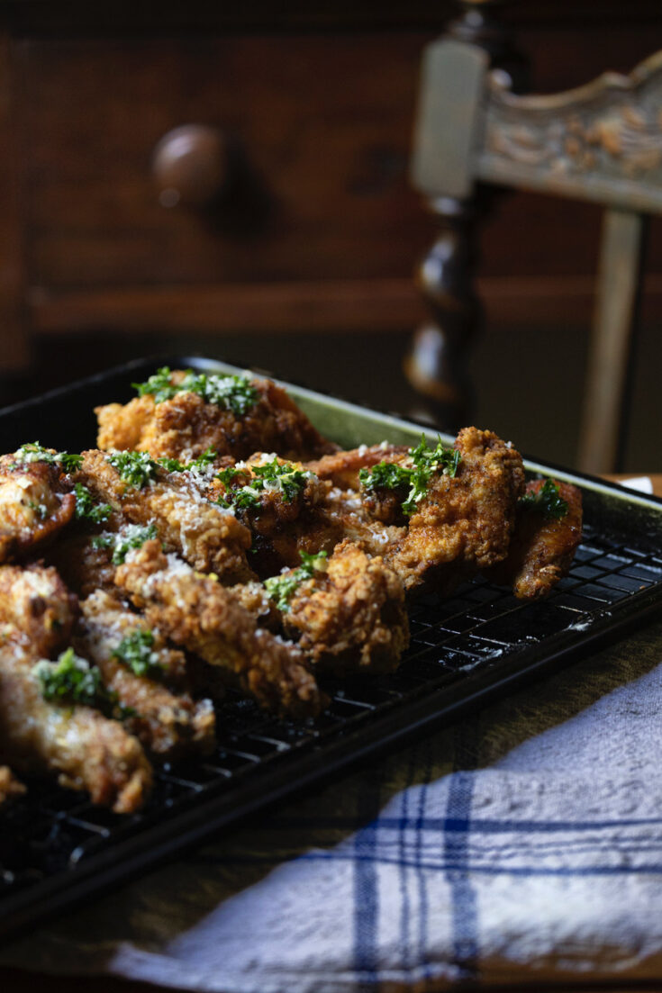 fried chicken wings with honey garlic sauce cooling on wire rack on kitchen table with striped blue cloth