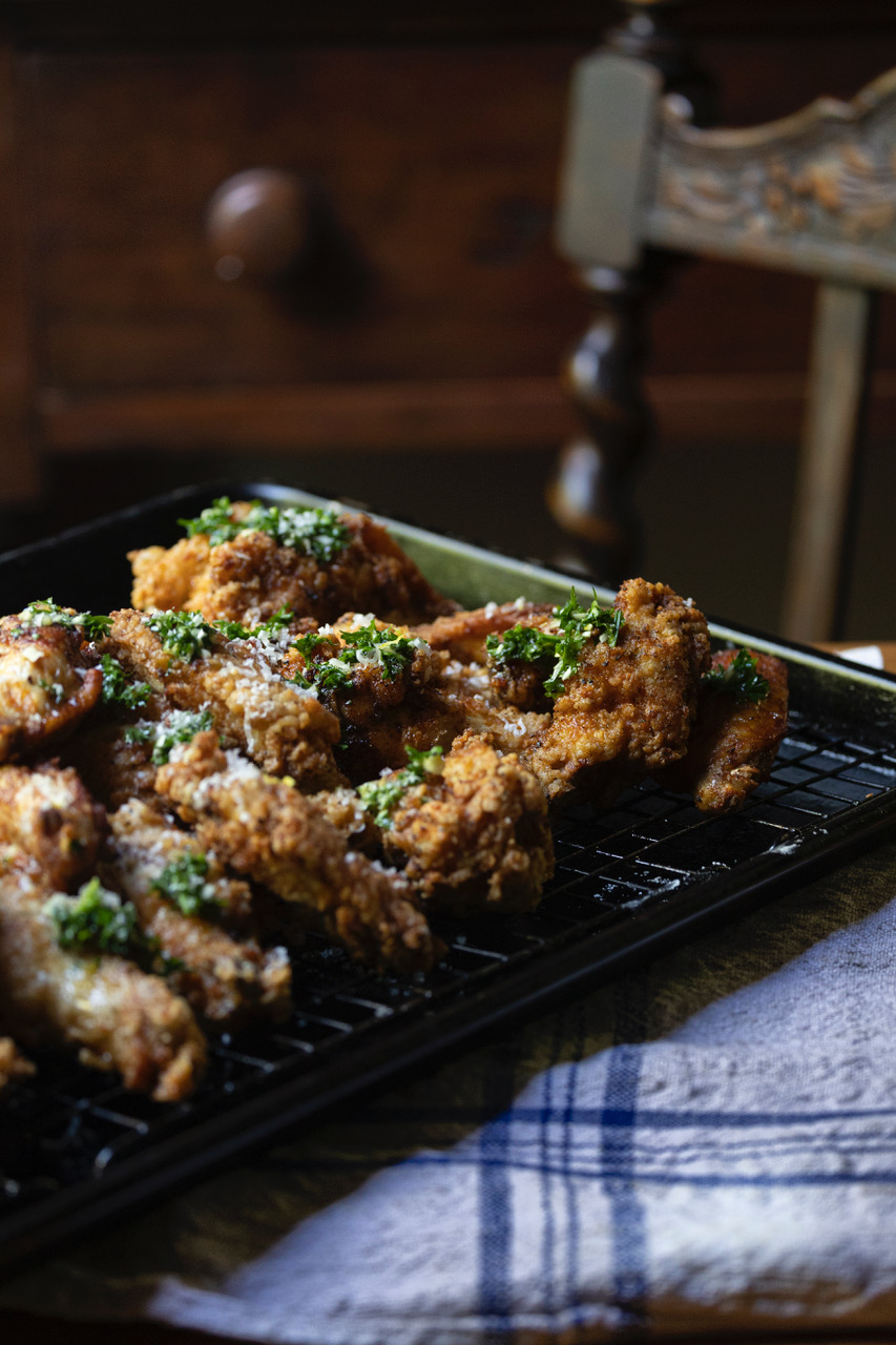 fried chicken wings with honey garlic sauce cooling on wire rack on kitchen table with striped blue cloth