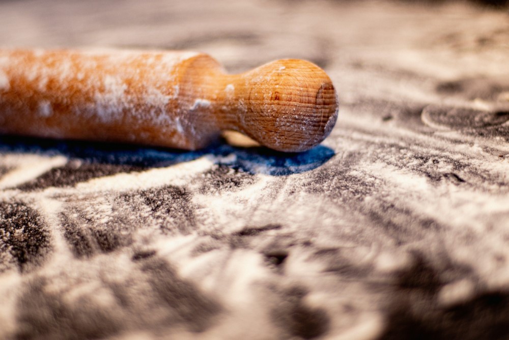 wooden rolling pin on kitchen counter with dusting of flour