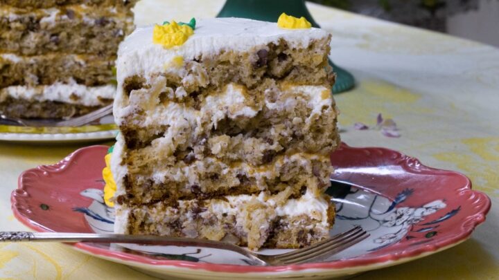 slice of 3-layer hummingbird cake on pink dessert plate with fork