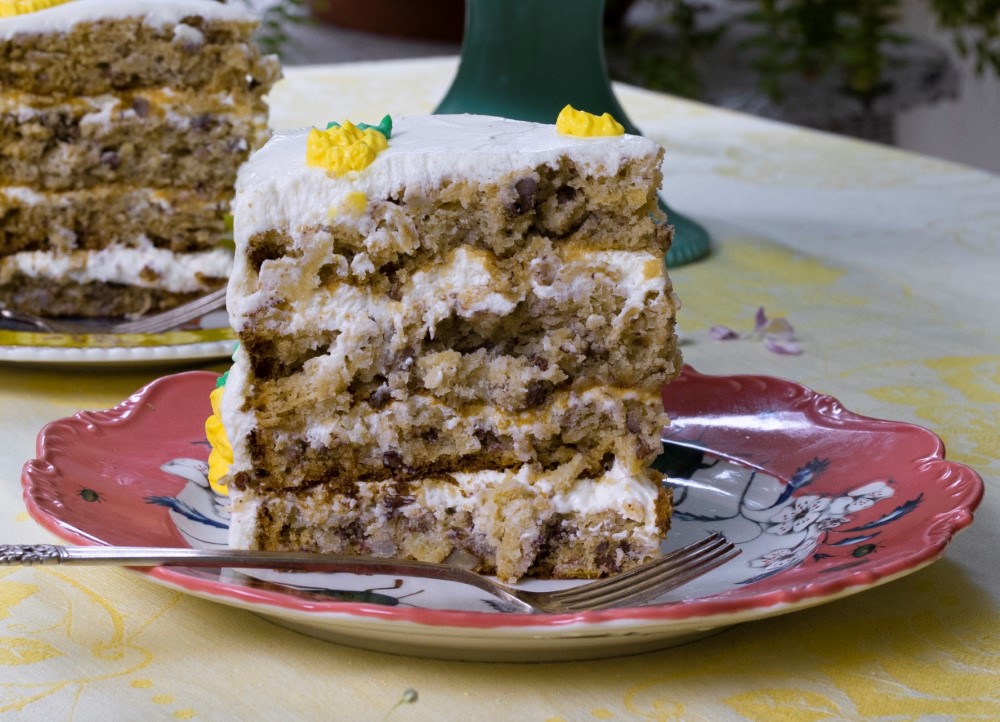 slice of 3-layer hummingbird cake on pink dessert plate with fork