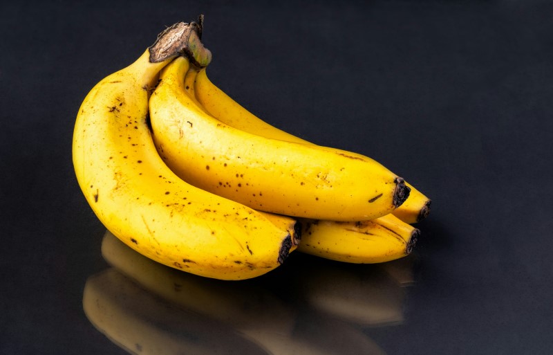 bunch of ripe bananas on dark countertop