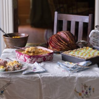 vertical photo of Easter table with southern glazed ham, casserole, and other dishes