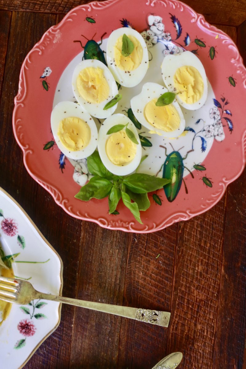 hard boiled eggs halved with green garnish on salmon colored plate