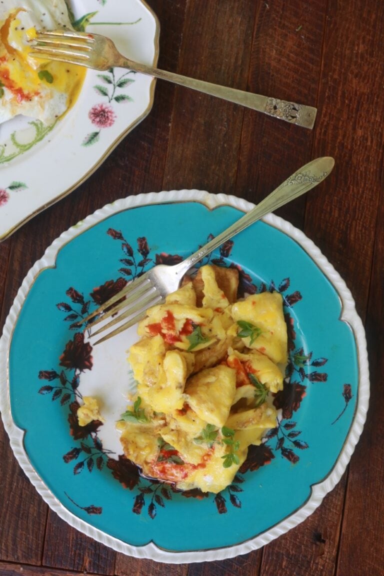 scrambled eggs on blue plate with tomato and garnish