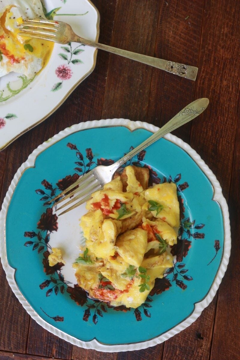 scrambled eggs on blue plate with tomato and garnish