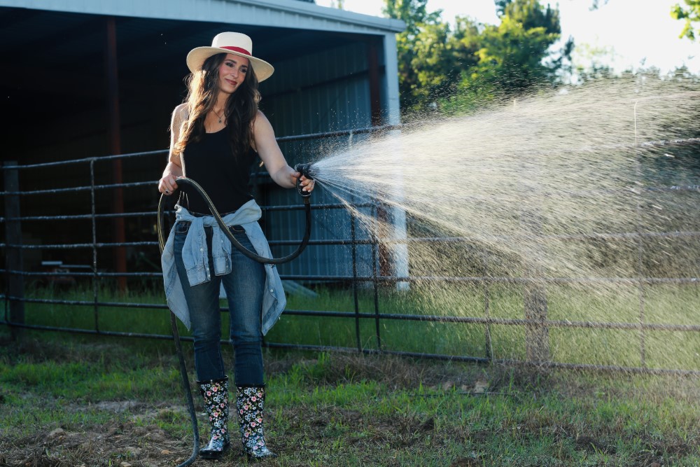 Stacy Lyn watering her garden with hose