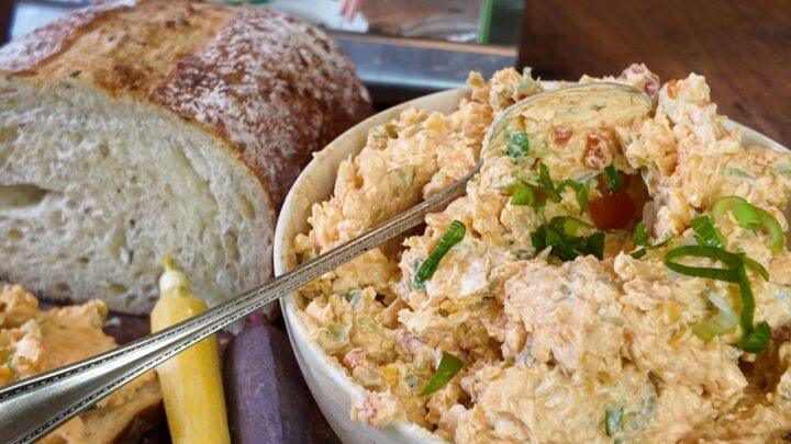 heaping bowl of pimento cheese spread on wooden cutting board with celery, bread, and crackers - Stacy Lyn's Love Language of the South cookbook in background
