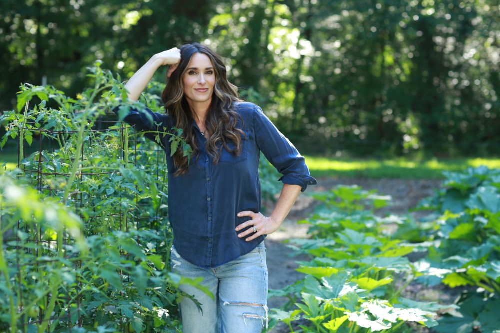 stacy lyn in garden leaning on wire frame trellis
