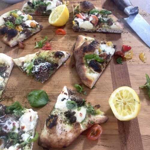 slices of homemade turkey pizza on cutting board with basil walnut pesto