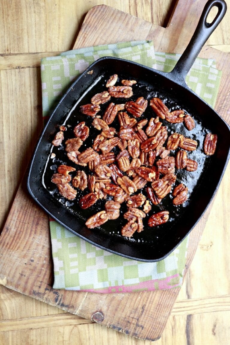 black skillet with candied pecans resting on green dishcloth