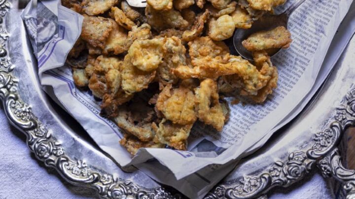 platter of golden fried pickles with fork and jar of creamy sauce on the side