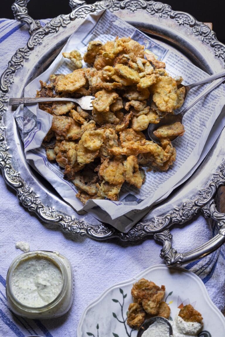 platter of golden fried pickles with fork and jar of creamy sauce on the side