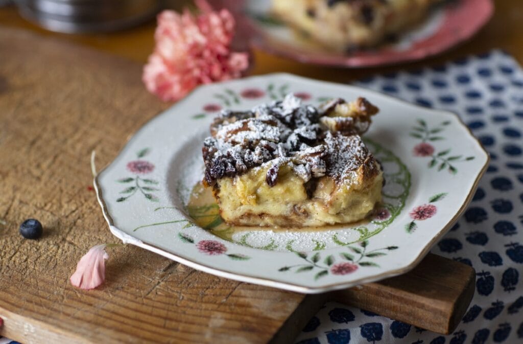 Stacy Lyn's bread pudding with bourbon sauce, served on a china plate with pink flowers, resting on a cutting board in kitchen