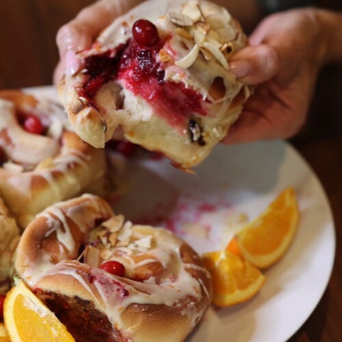 cranberry orange sticky bun broken apart to show bright red cranberry filling