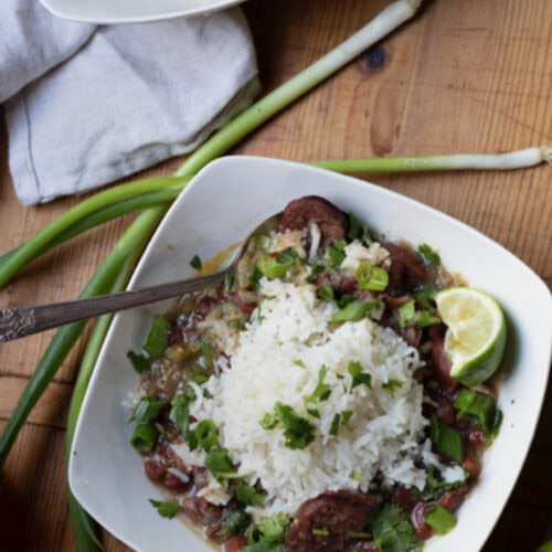 New Orleans red beans rice in square white bowl on rustic wooden table with another bowl in background