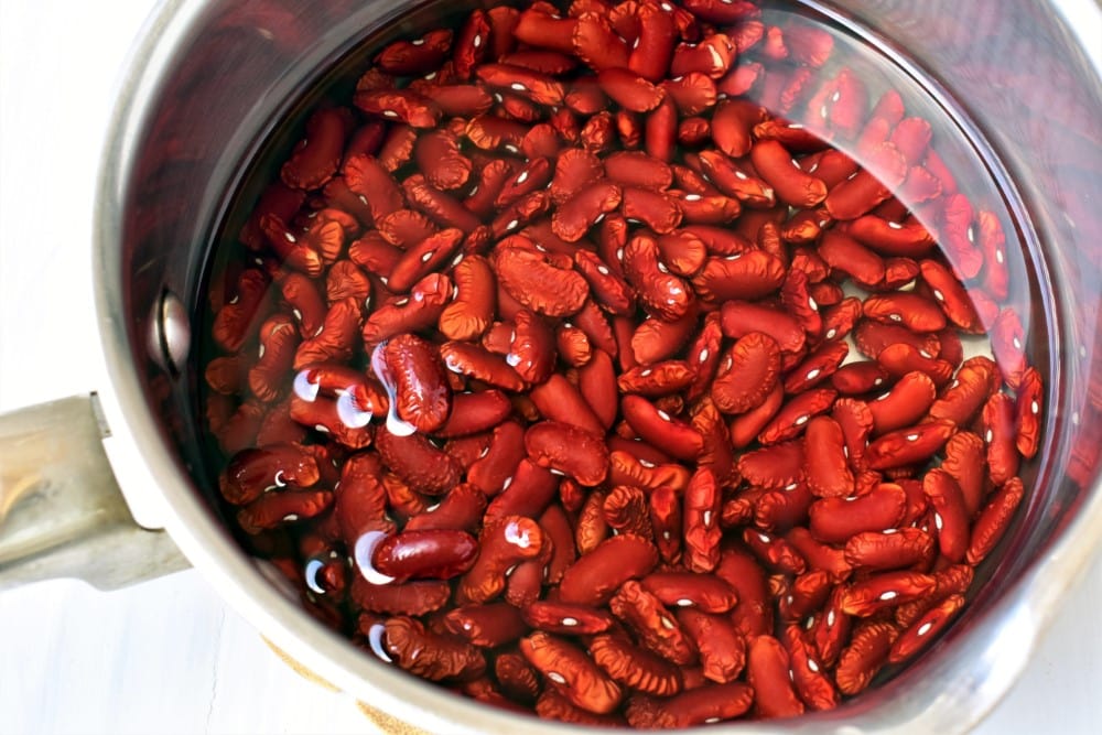 closeup of red beans soaking in water in stainless steel pot
